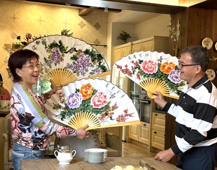 Two people holding floral folding fans